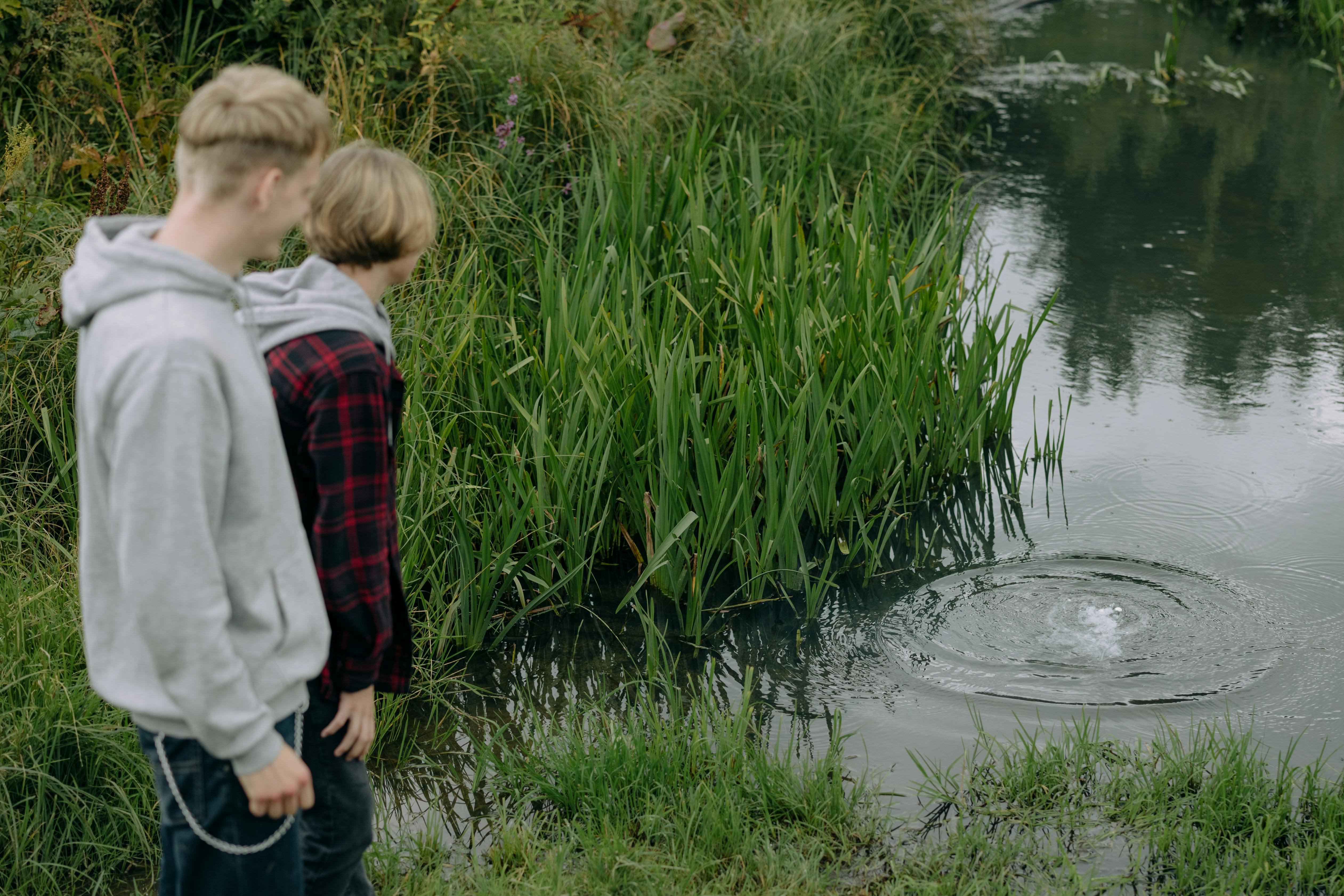 boys standing near body of water