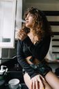 Woman in a Black Crop Top Smoking Near a Window
