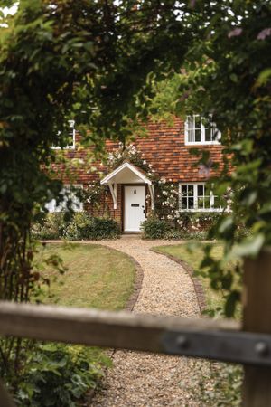 Gravel path curving to a brick cottage — photo by Olga Lioncat on Pexels
