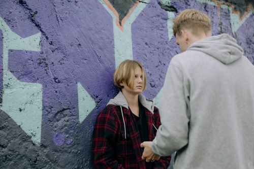 Free Two teenagers engage in a serious conversation by a vibrant graffiti wall. Stock Photo