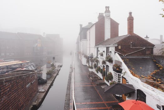 A misty canal scene in Birmingham, UK, showcasing historic buildings along the waterside pathway.