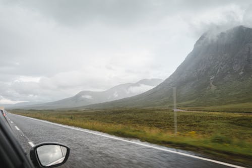 Car driving near mountains on cloudy day
