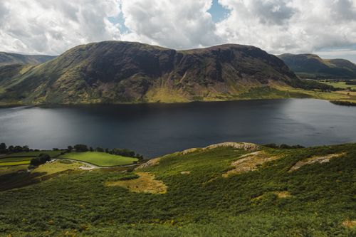 Free High angle of calm lake located amidst hills with grassy slopes on cloudy day Stock Photo