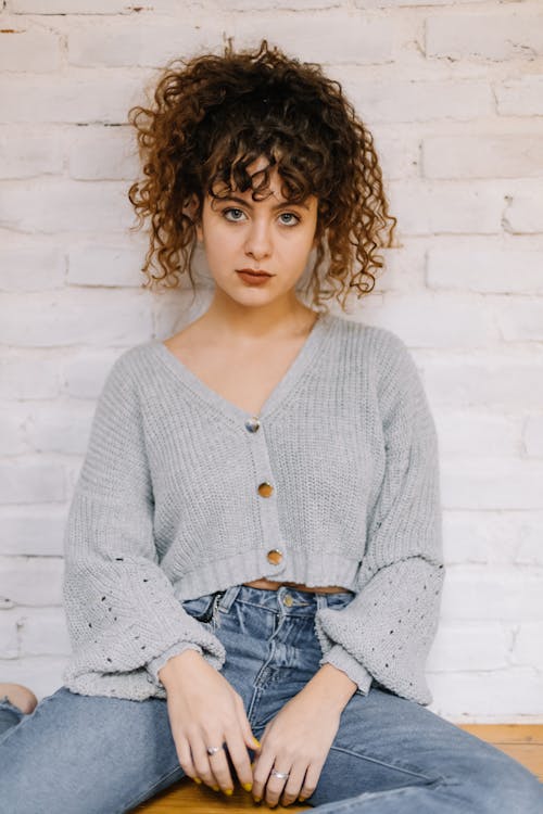 Free Woman with Curly Hair Wearing a Gray Knitted Sweater  Stock Photo