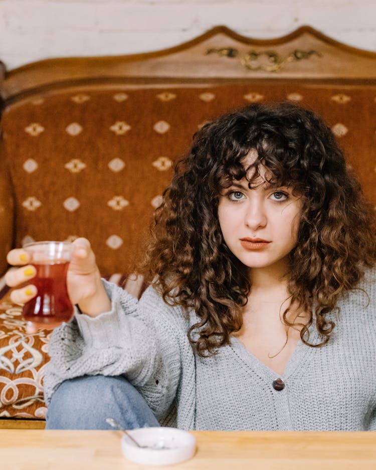 Pretty Woman Holding A Glass Of Drink While Looking At Camera