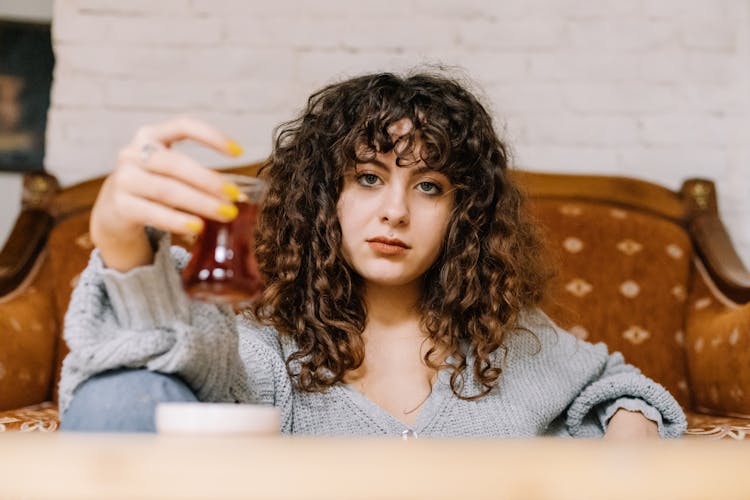 Pretty Woman Holding A Glass Of Drink While Looking At Camera