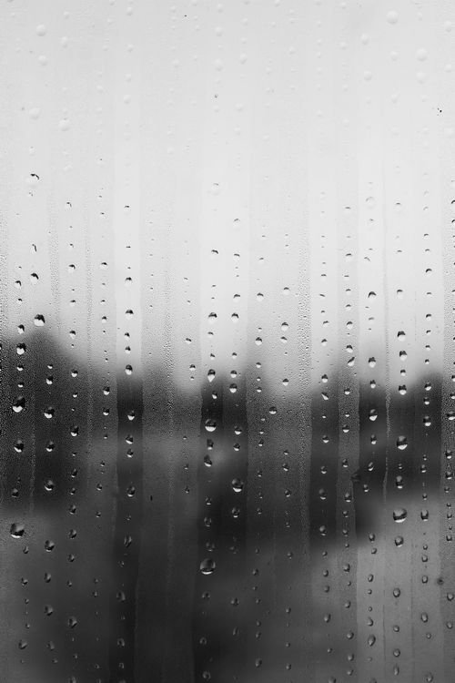 Free Close-up of raindrops on a glass window in grayscale, creating a moody atmospheric effect. Stock Photo