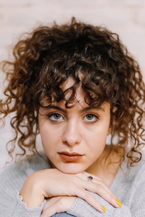 Free Close-Up Shot of a Curly-Haired Woman Looking at Camera Stock Photo