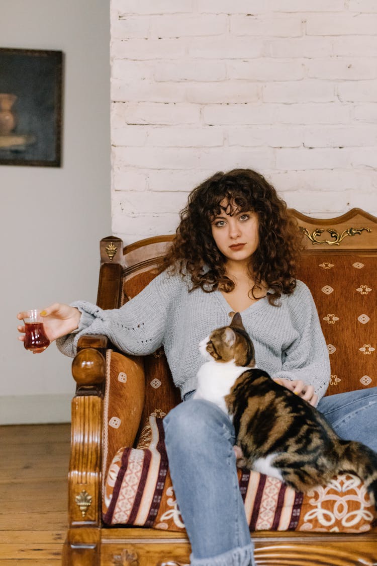 A Woman Sitting On A Couch With Her Pet Cat