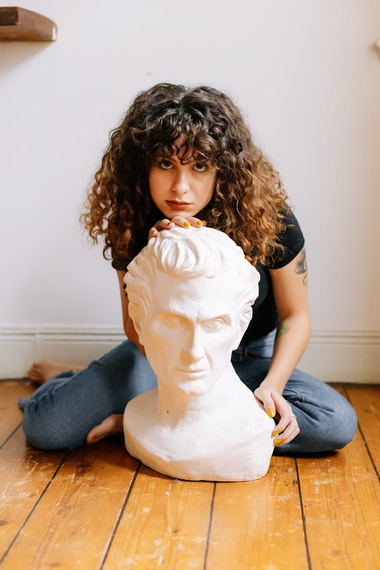 A Woman Sitting On The Floor With A Bust