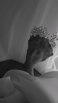 Elegant black and white image of a sculpture adorned with delicate flowers.