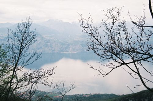 Free Tranquil scene of Lake Garda, Italy, with misty mountains and barren trees. Stock Photo