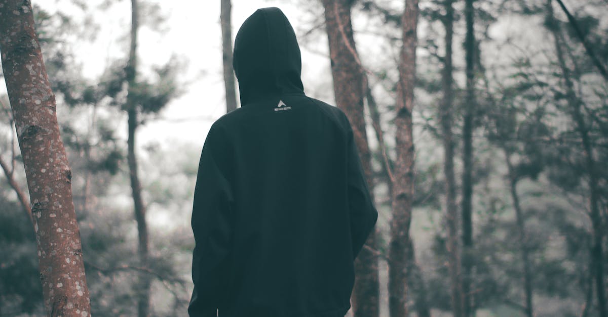 Man Wearing Black Hoodie With Black Pants Standing in the Middle of Forest