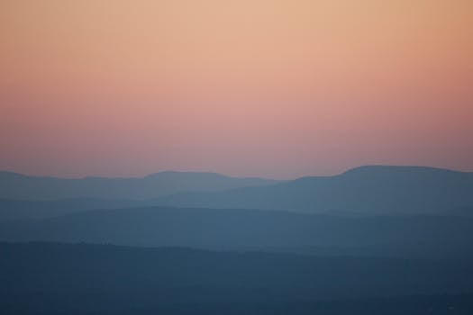 Peaceful twilight scene with mountains and a gradient sky fading from orange to blue.