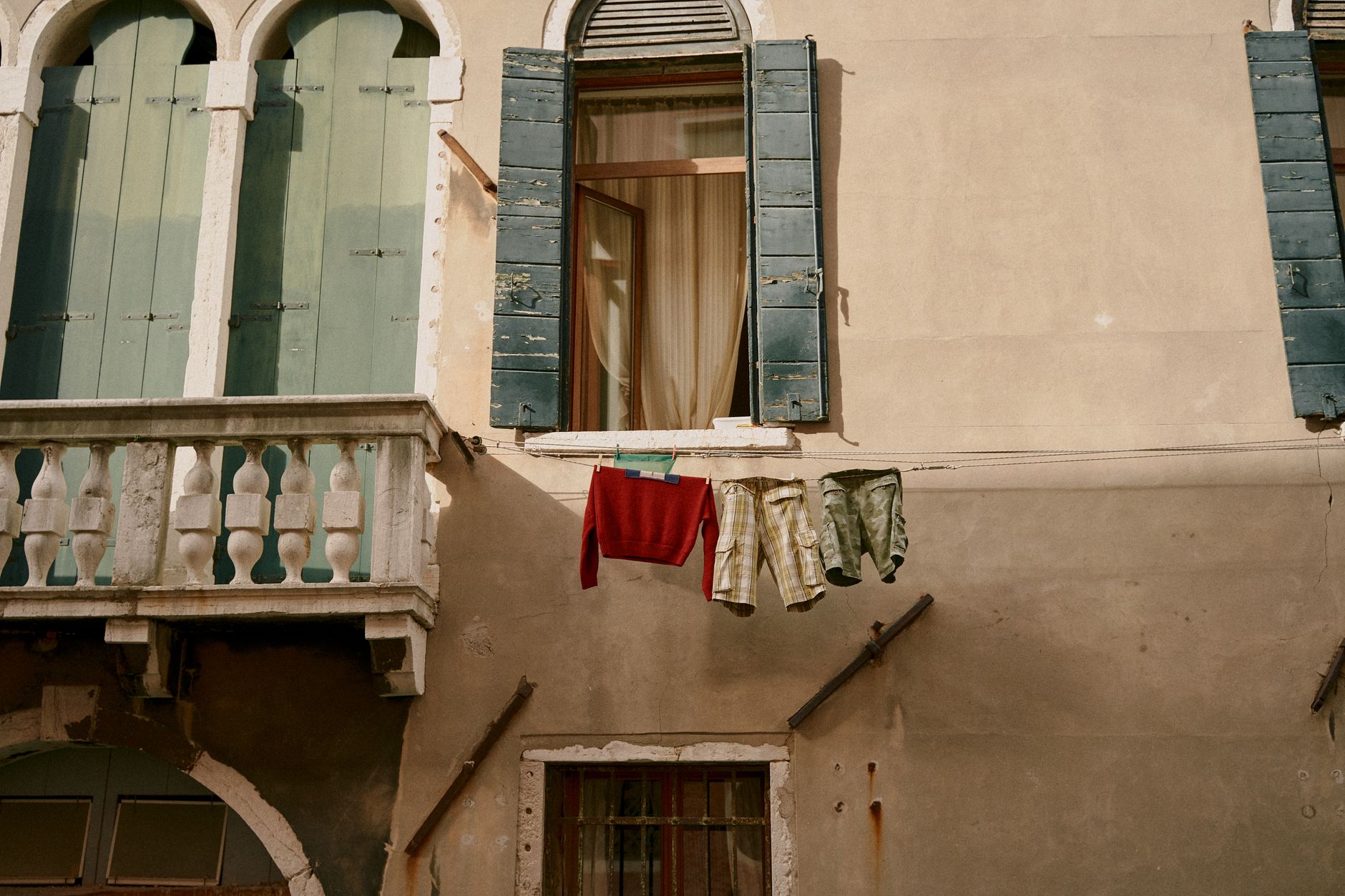 Exterior of old apartment building with arched windows and small balcony near drying laundry