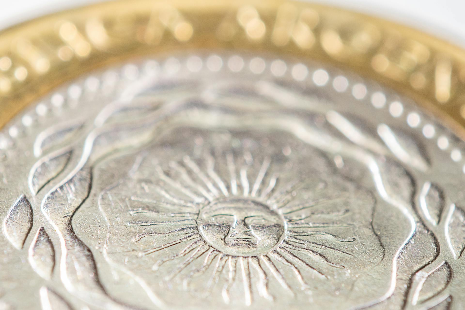 Close-up of a detailed bimetallic coin featuring a sun design, highlighting texture and pattern.