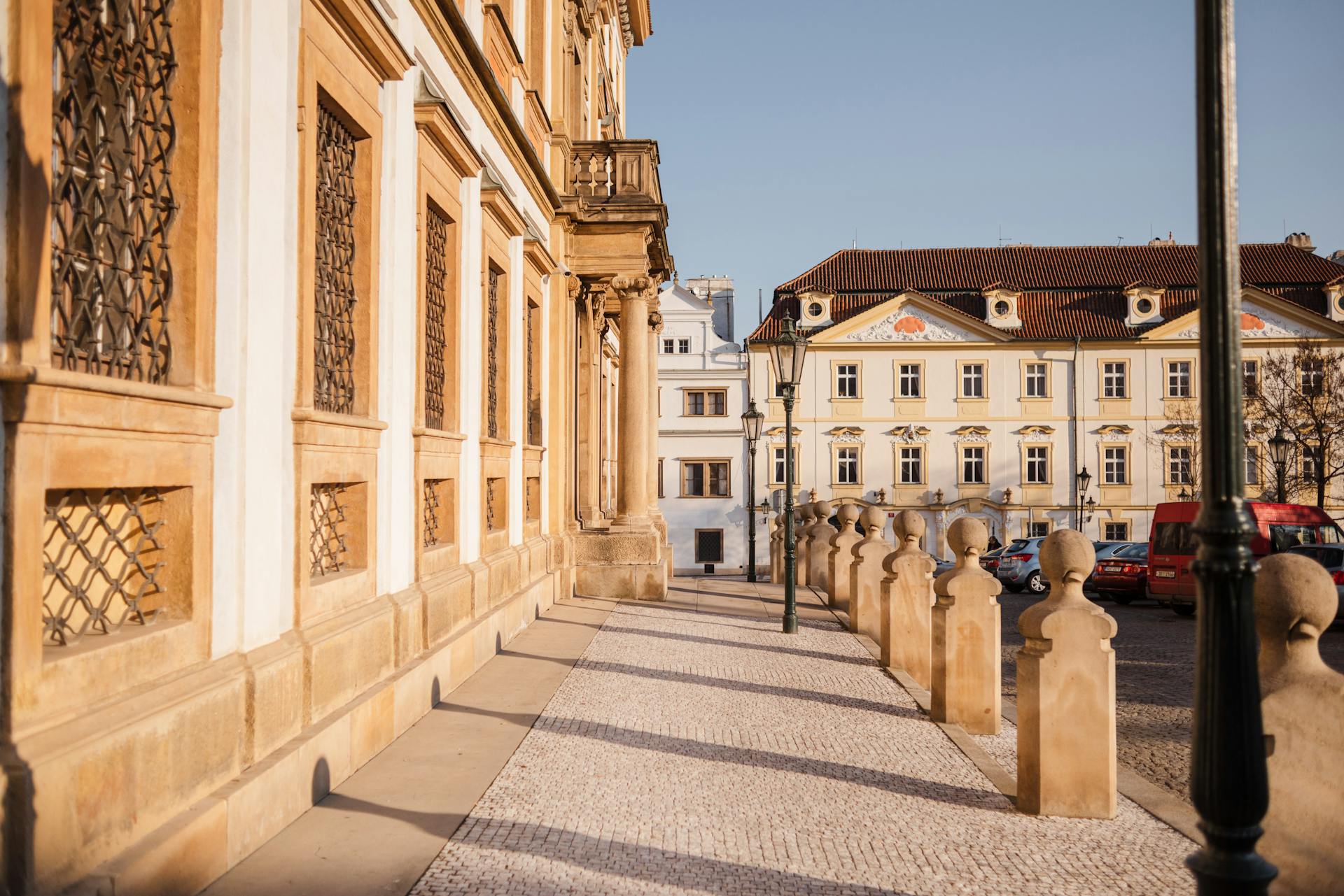 Empty walkway with shadows and old masonry house exteriors with fenced windows in sunny city