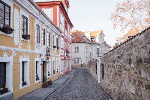 Cobblestone walkway between stone wall and aged house exteriors with ornament in fall in Prague Czech Republic