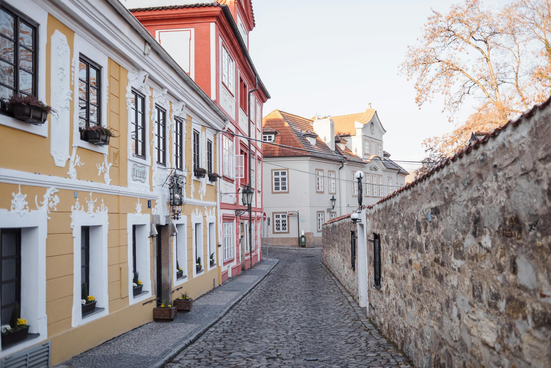 Cobblestone walkway between stone wall and aged house exteriors with ornament in fall in Prague Czech Republic