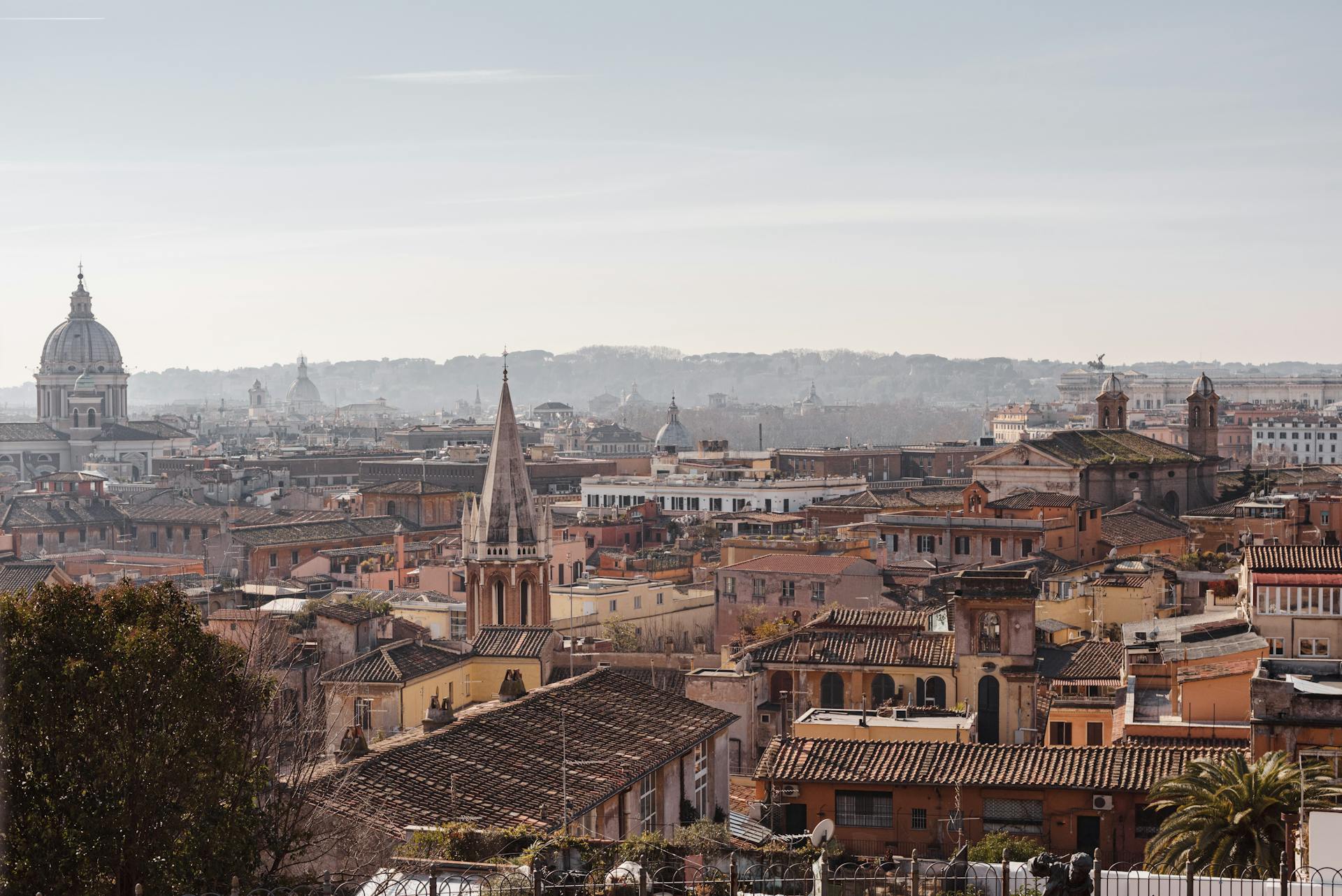 Cityscape with church and aged residential building facades with ribbed roofs under cloudy sky on sunny day