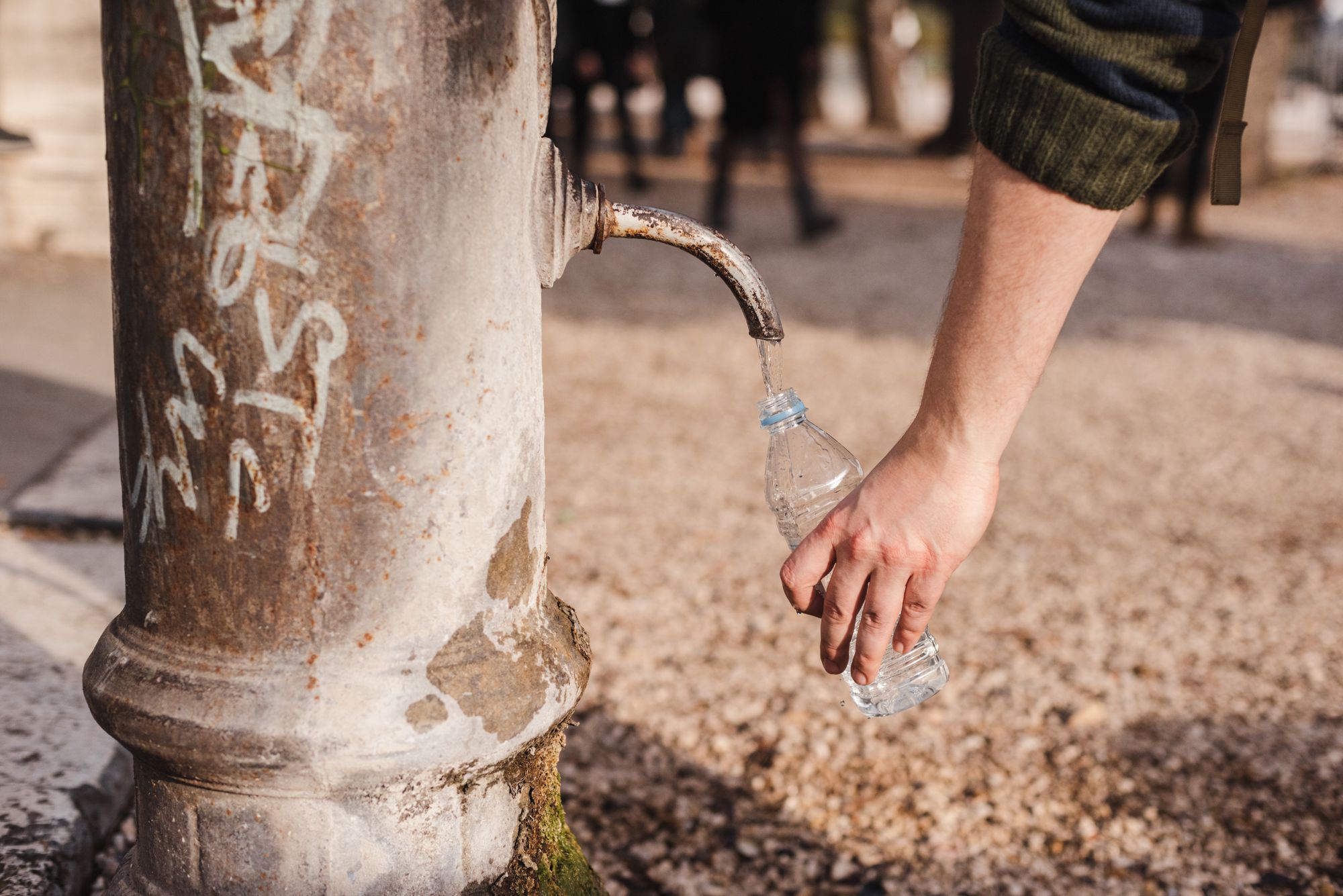 Persona llenando una botella de agua bajo el sol en un día caluroso