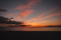 Scenic view of fluffy clouds in sky over wavy ocean and coast silhouette at sundown