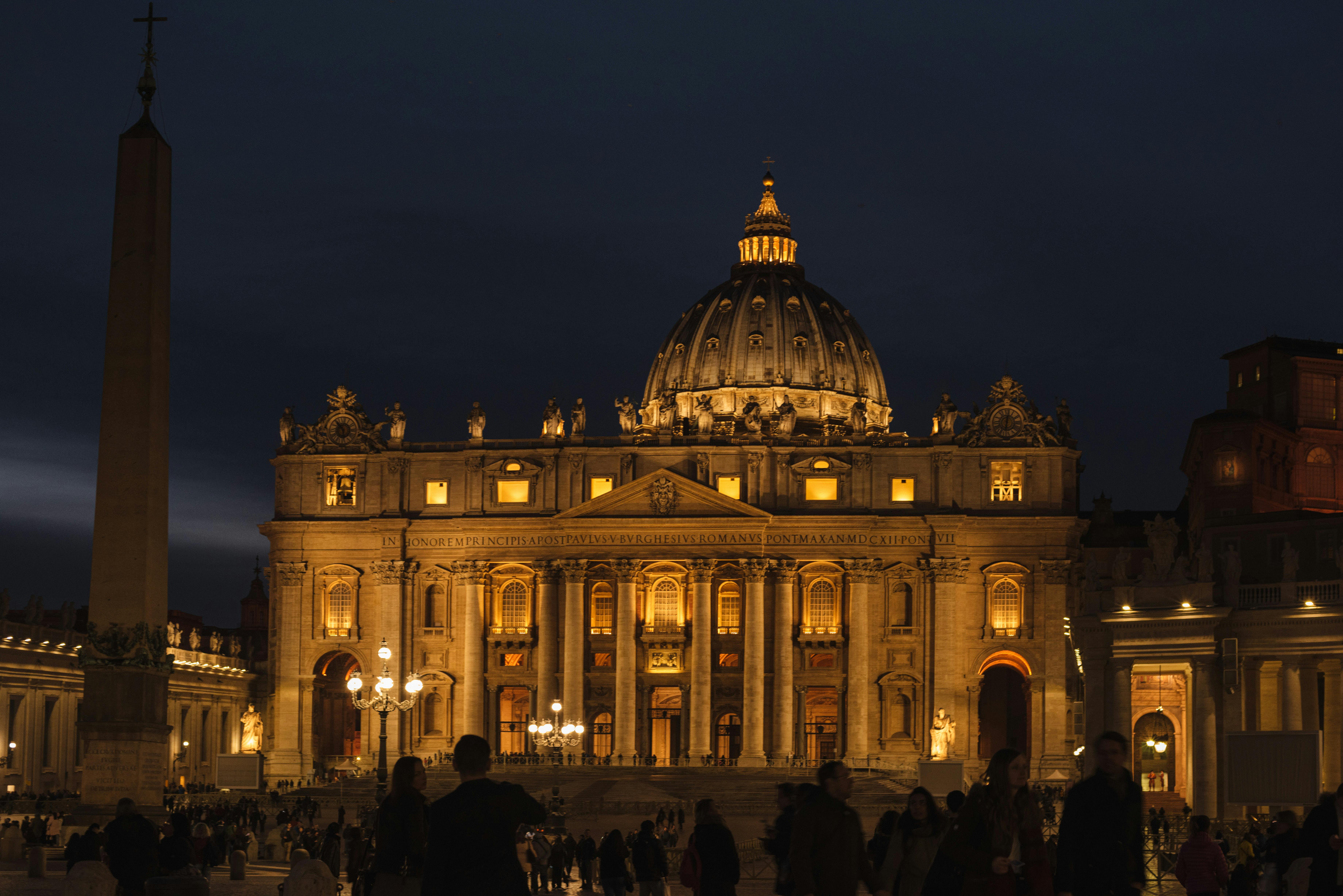 st peters basilica facade against unrecognizable citizen silhouettes at night