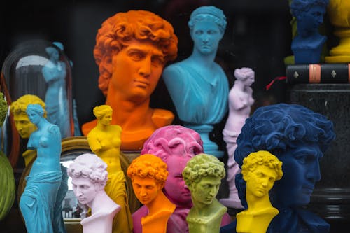 Free Multicolored head sculptures of David near bright statuettes placed in store with abundance of souvenirs and black pillar with book Stock Photo