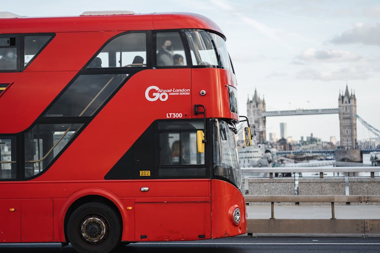 Modern Bus Driving Along River Against Bridge