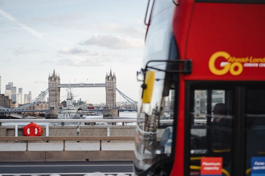 Iconic Tower Bridge in London with a red bus passing by on a clear day.