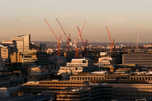 Skyline of London with construction cranes at sunset, showcasing modern architecture and urban development.