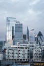 Contemporary multistory commercial office buildings with glass walls located on street in financial district of London city against cloudy sky
