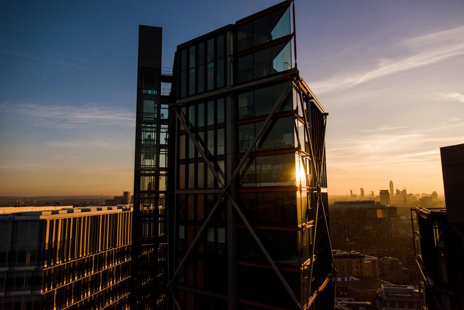 Geometric facade of modern multistory residential building with glass walls and outdoor elevator located in London against cloudy sunset sky