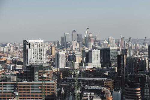 Scenic cityscape of London district with contemporary multistory buildings and crane towers under cloudy sky in daylight