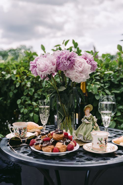 Plate of yummy pastries with wineglasses served on table with bouquet