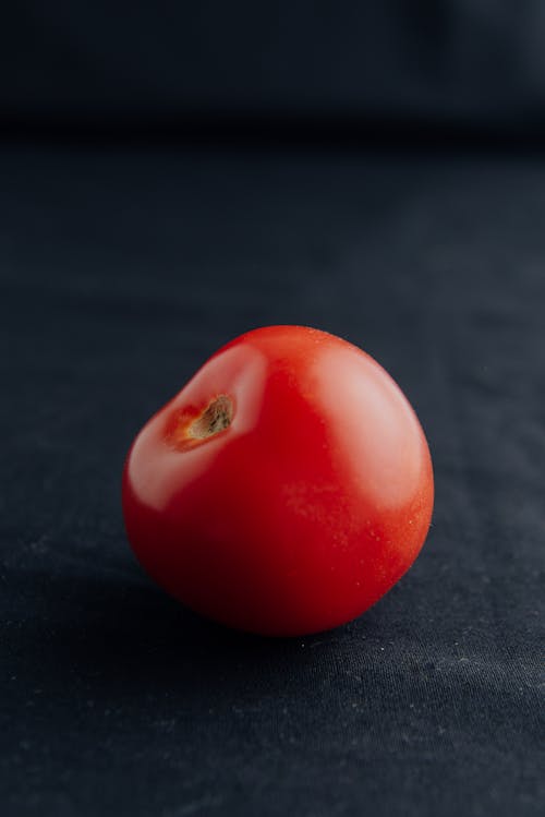 Free Ripe red whole tomato prepared for cooking and placed on black background of studio Stock Photo
