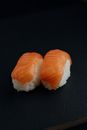 From above of delicious fresh sushi with white rice and tasty salmon on black background