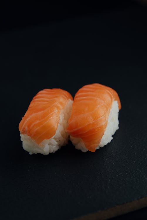Free From above of delicious fresh sushi with white rice and tasty salmon on black background Stock Photo