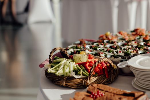Cut celery with asparagus and bell pepper placed on buffet table near bowls with tasty dishes in cafe on blurred background