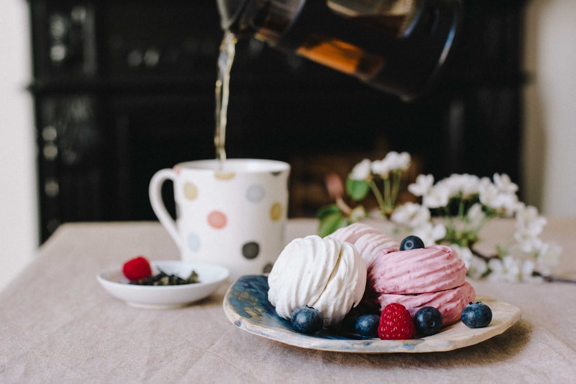 Free Cup filling with hot tea near plate with delicate zephyrs Stock Photo