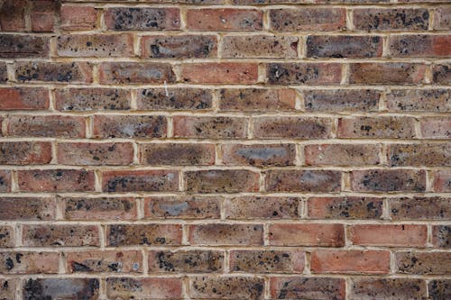 Simple textured wall with brown rough bricks of house on street in daytime
