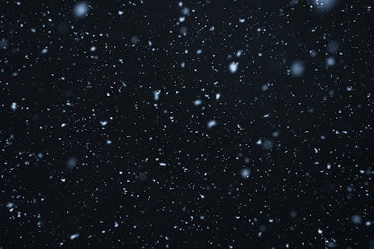 A mesmerizing view of snowflakes falling against a dark, starry night sky.