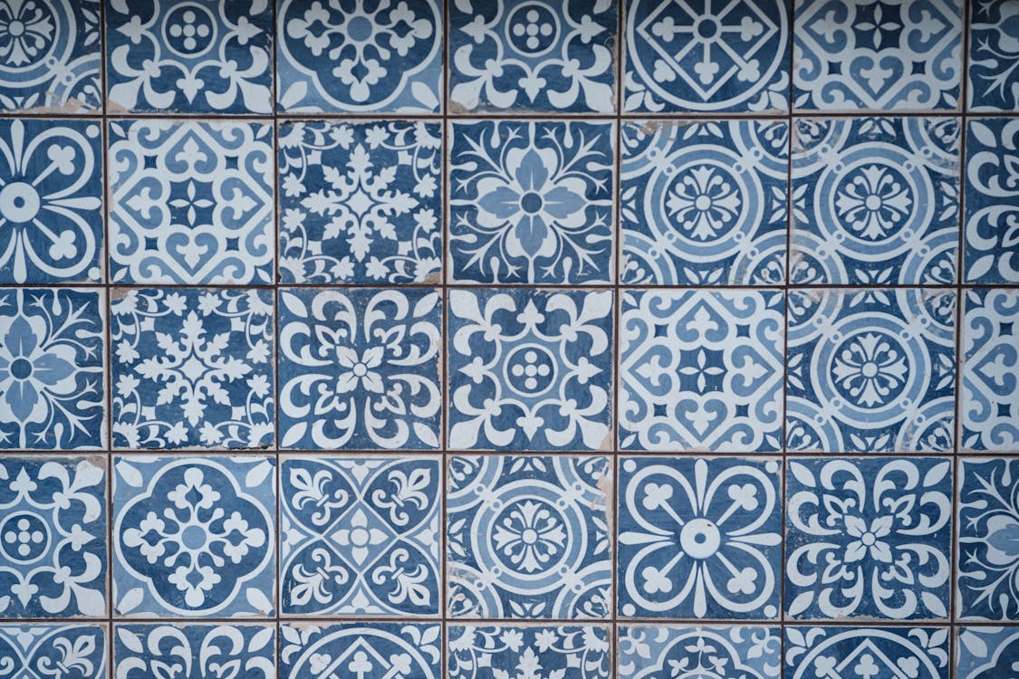 Aged wall covered with ceramic square shaped tile with many blue different ornaments