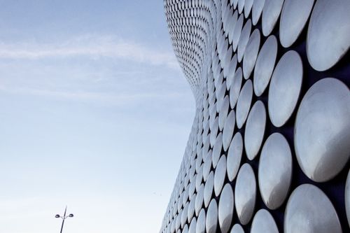 Free Low angle view of a modern building facade featuring circular geometric patterns against a clear sky. Stock Photo