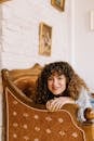 Woman in White Long Sleeve Shirt Sitting on Brown Wooden Chair