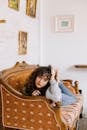 Girl in Gray Sweater Sitting on Brown Wooden Bed