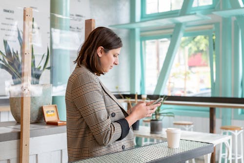 Woman in Plaid Coat Using Cellphone