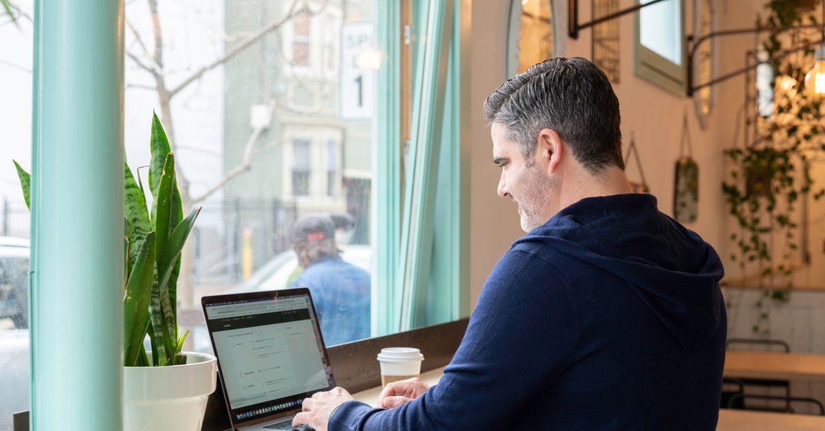 Someone working on a laptop at a table in a city cafe.