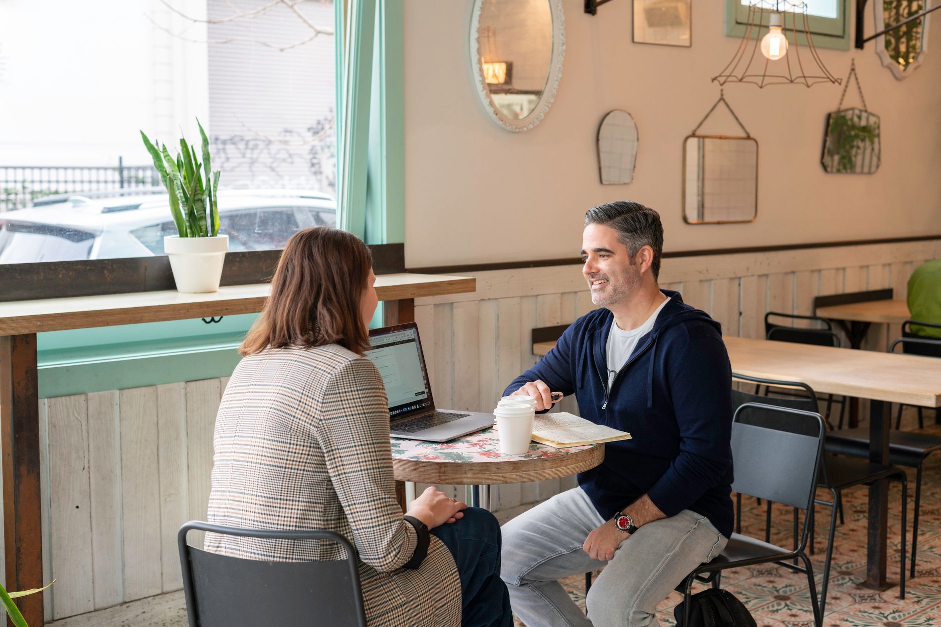 A coach and a client talking across a cafe table, the conversation a package sale usually starts with