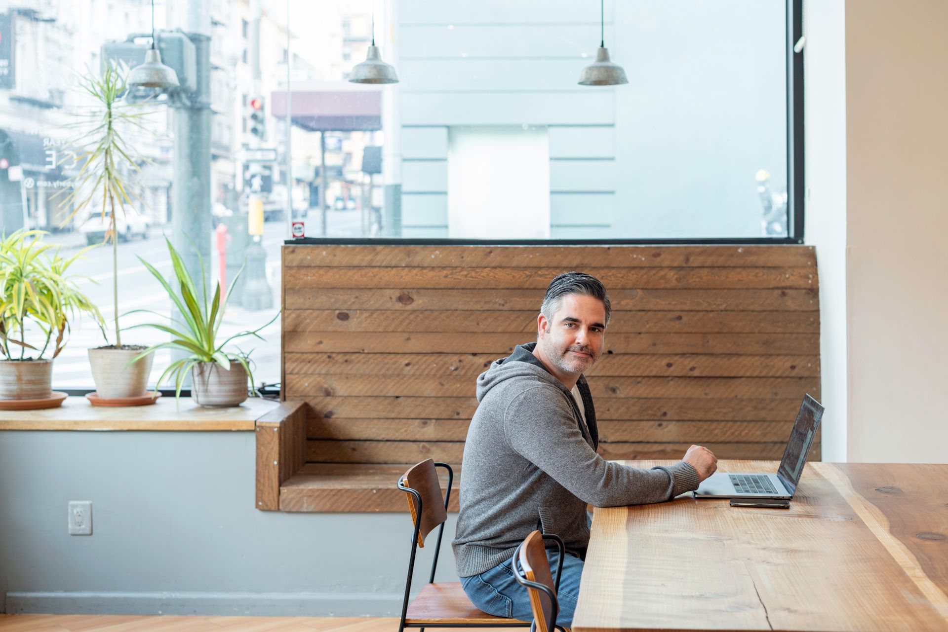 Adult man working on a laptop in a stylish coffee shop setting, ideal for remote work themes.